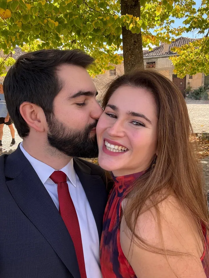 Un beso y una sonrisa bajo los árboles.