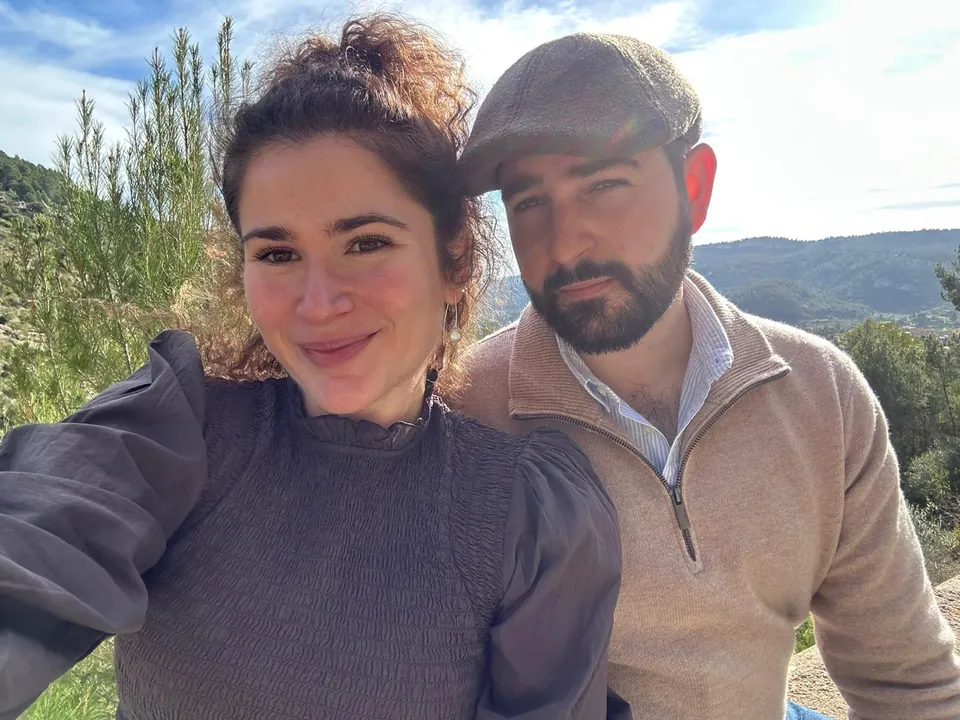 Raquel y Adrián al aire libre, con montañas al fondo.